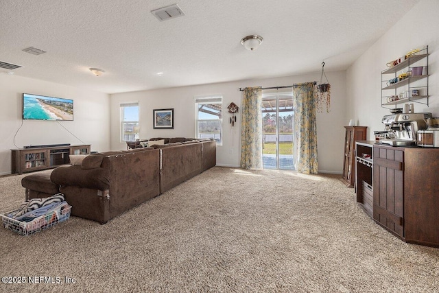 living area with light colored carpet, visible vents, and a textured ceiling