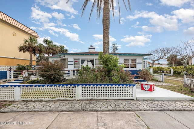 view of front of house featuring a fenced front yard, a chimney, and stucco siding