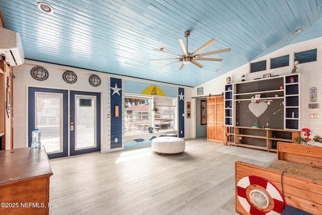 living area with a barn door, wood finished floors, vaulted ceiling, french doors, and a wall mounted AC