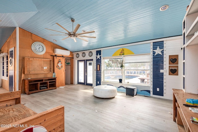 living area with french doors, lofted ceiling, a wall mounted AC, light wood-style floors, and ceiling fan