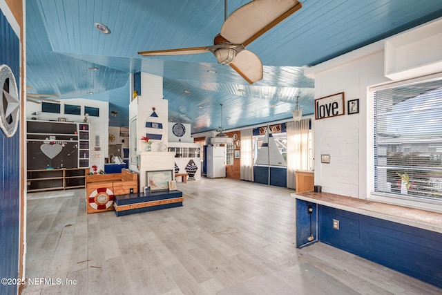 interior space with lofted ceiling, ceiling fan, light wood-type flooring, and a wealth of natural light