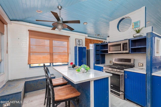 kitchen featuring open shelves, lofted ceiling, light countertops, appliances with stainless steel finishes, and a kitchen island