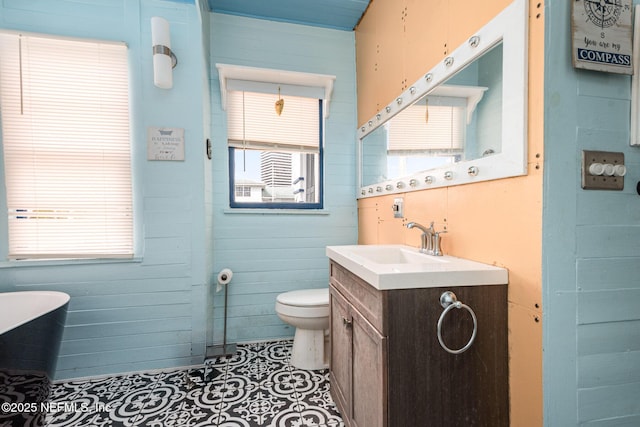 bathroom with a wealth of natural light, a freestanding tub, vanity, and toilet