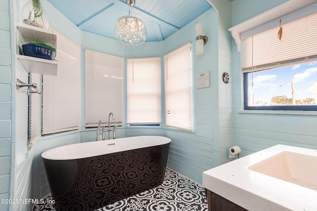 bathroom featuring a chandelier, a freestanding bath, and vanity