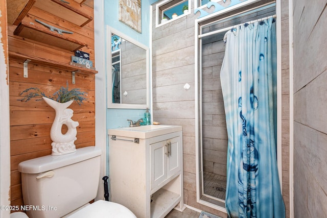 bathroom featuring toilet, wood walls, a shower stall, and vanity