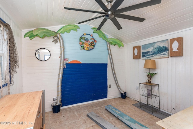 interior space featuring lofted ceiling, wood ceiling, ceiling fan, and wooden walls