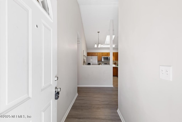 corridor featuring a chandelier, dark wood finished floors, and baseboards