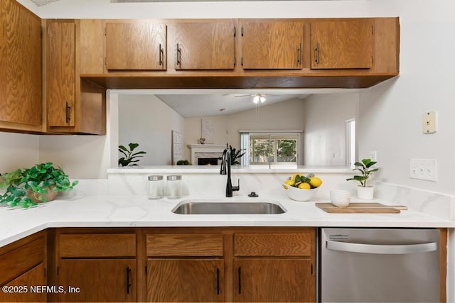 kitchen with lofted ceiling, a sink, light countertops, brown cabinets, and dishwasher