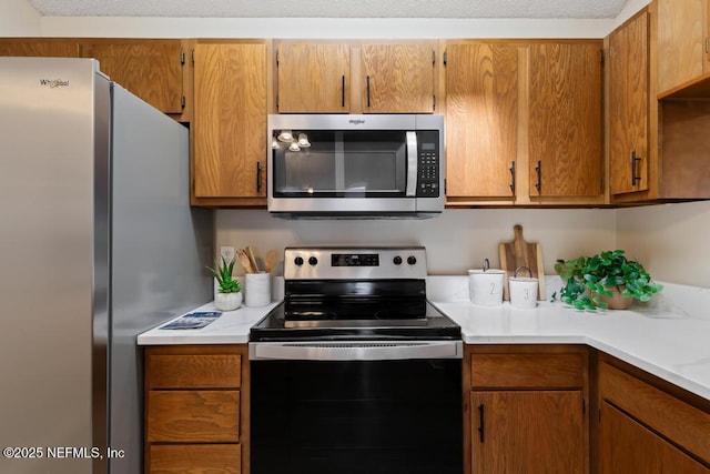 kitchen with stainless steel appliances, brown cabinets, and light countertops