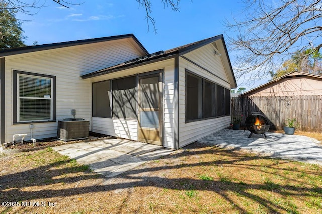 rear view of house featuring a patio, an outdoor fire pit, a sunroom, fence, and cooling unit