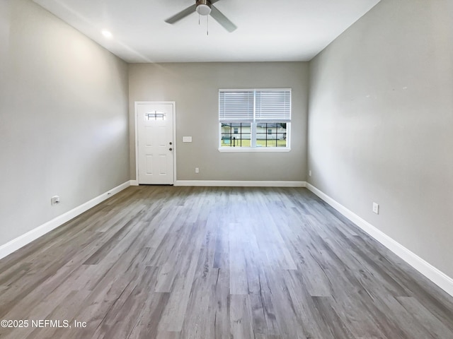 empty room featuring ceiling fan, light wood-style flooring, and baseboards