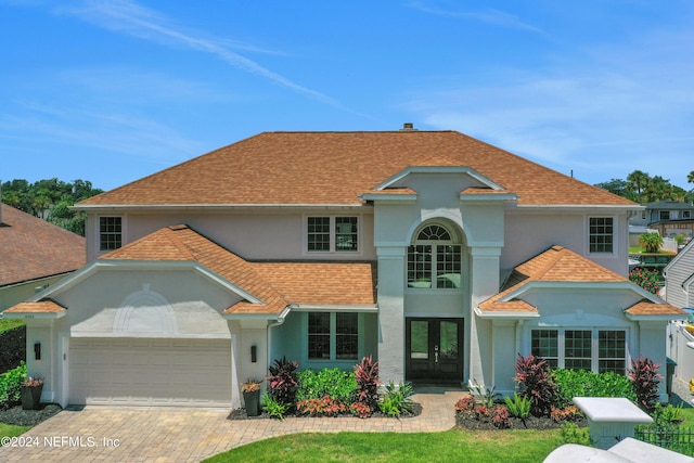 view of front of house with an attached garage, a shingled roof, decorative driveway, and stucco siding