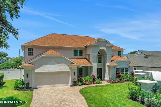 mediterranean / spanish house with decorative driveway, stucco siding, an attached garage, a front yard, and fence