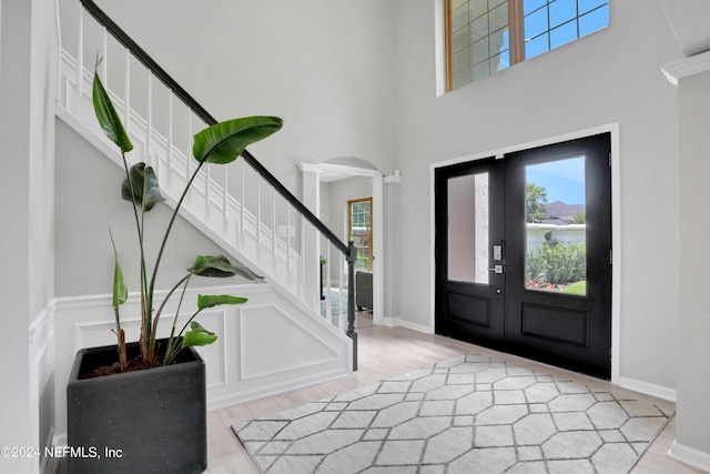 foyer featuring light wood-type flooring, french doors, stairway, and plenty of natural light