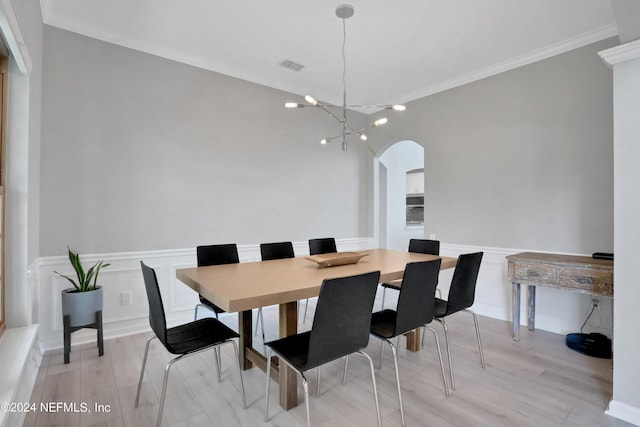 dining area with arched walkways, visible vents, ornamental molding, wainscoting, and a chandelier