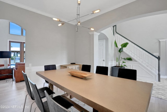 dining area with arched walkways, a decorative wall, stairway, light wood finished floors, and ornate columns