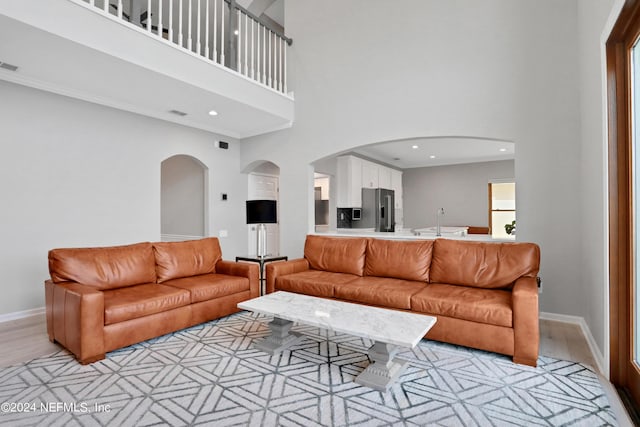 living area with light wood finished floors, baseboards, a high ceiling, and visible vents