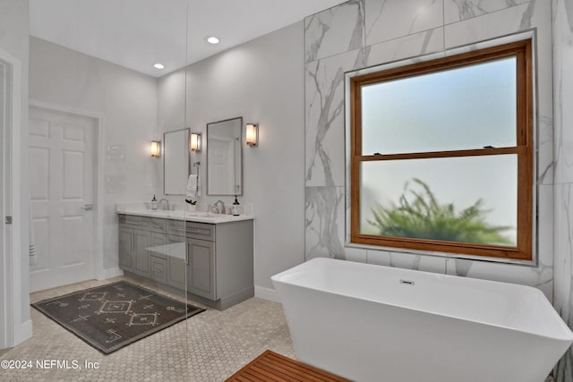 bathroom featuring recessed lighting, a freestanding tub, a sink, and double vanity