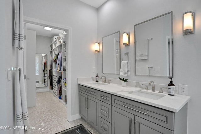 bathroom featuring double vanity, tile patterned flooring, a sink, and a walk in closet