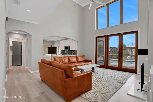 living area featuring light wood finished floors, visible vents, arched walkways, baseboards, and ceiling fan