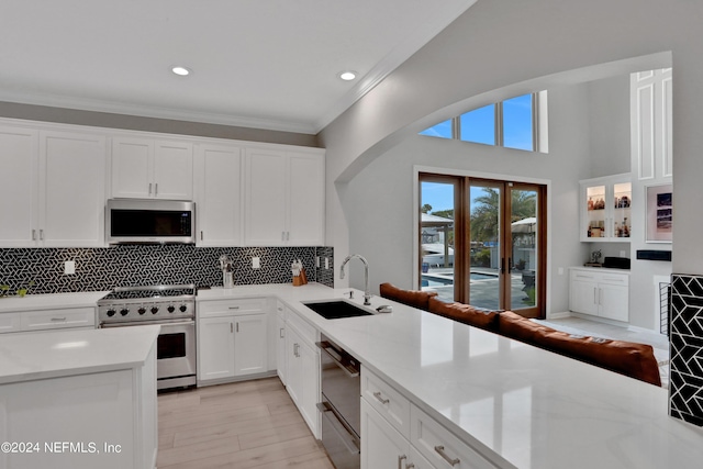 kitchen featuring a sink, white cabinets, appliances with stainless steel finishes, ornamental molding, and tasteful backsplash