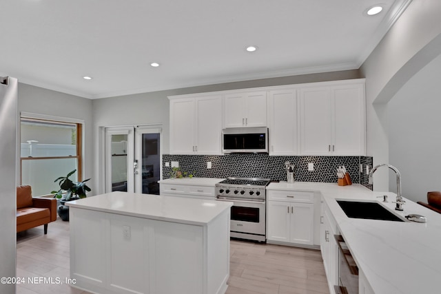 kitchen featuring tasteful backsplash, white cabinetry, a sink, and high end stainless steel range