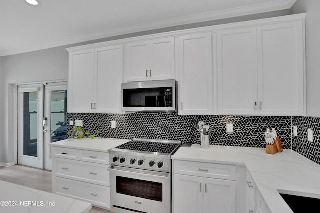 kitchen featuring white cabinets, backsplash, stainless steel appliances, and crown molding