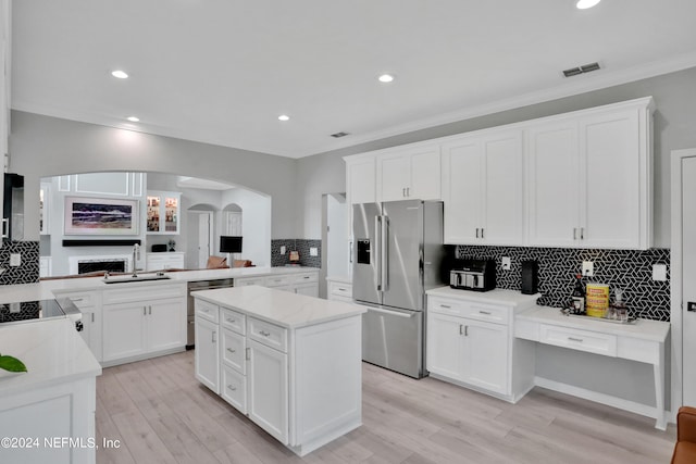 kitchen with stainless steel appliances, a kitchen island, a sink, and white cabinetry