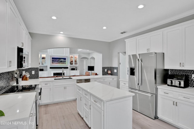 kitchen featuring white cabinets, light stone counters, stainless steel appliances, and a center island