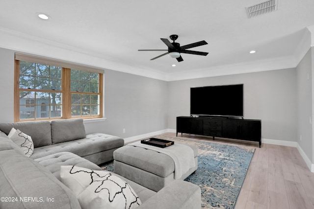 living area with crown molding, light wood finished floors, visible vents, a ceiling fan, and baseboards