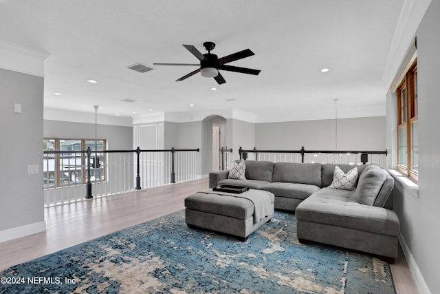 living area featuring a ceiling fan, visible vents, baseboards, and wood finished floors