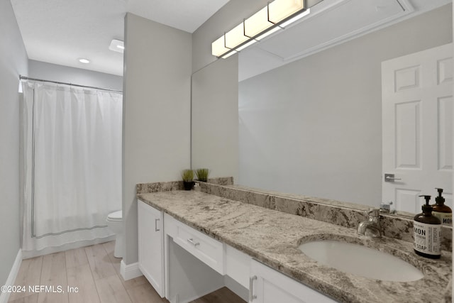 bathroom with shower / bath combination with curtain, toilet, vanity, wood finished floors, and baseboards