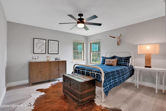 bedroom with ceiling fan, light wood-style flooring, and baseboards