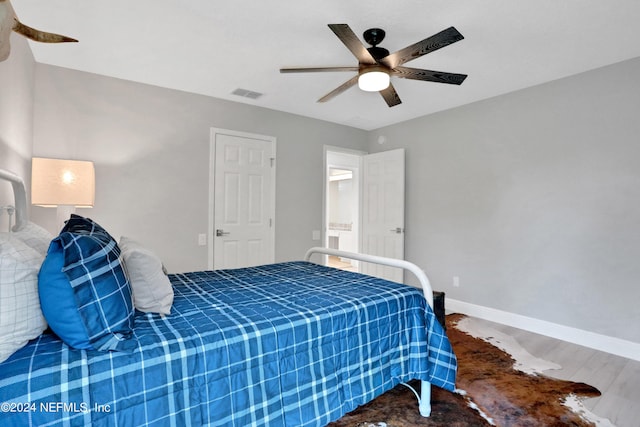 bedroom featuring ceiling fan, wood finished floors, visible vents, and baseboards