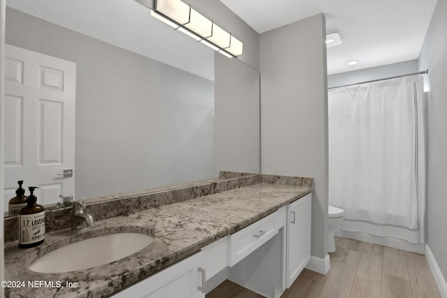 full bath with toilet, shower / bath combo, vanity, wood finished floors, and baseboards