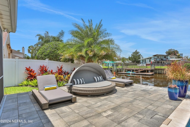 view of patio featuring a boat dock, a water view, and a fenced backyard