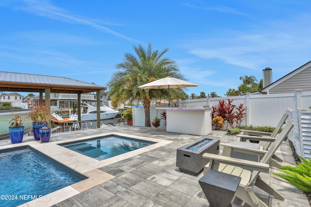 pool featuring an outdoor fire pit, a patio area, fence, and an in ground hot tub