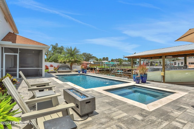 view of swimming pool with a fenced in pool, a water view, an outdoor fire pit, a sunroom, and an in ground hot tub