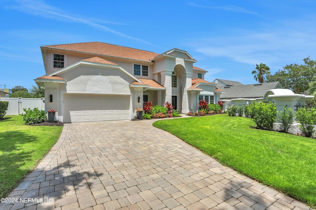 view of front facade with decorative driveway, an attached garage, fence, and a front yard