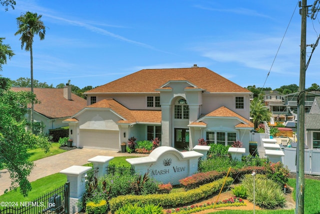 view of front of home featuring a fenced front yard, an attached garage, decorative driveway, a residential view, and stucco siding