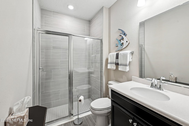 bathroom featuring wood finished floors, a shower stall, toilet, and vanity