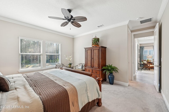 bedroom featuring baseboards, visible vents, light colored carpet, ornamental molding, and a textured ceiling