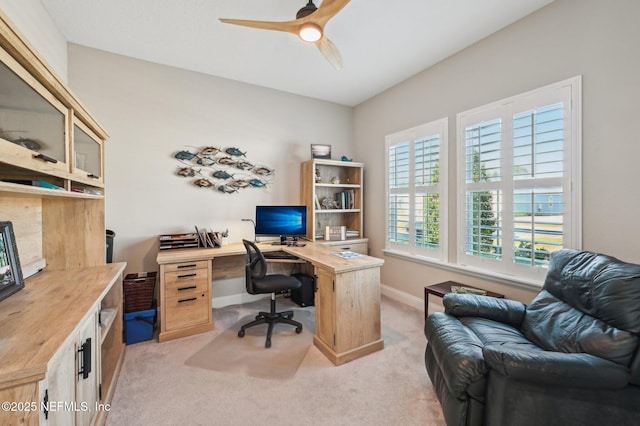 home office featuring a ceiling fan, light colored carpet, and baseboards