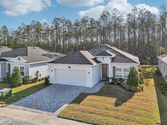 ranch-style home featuring decorative driveway, an attached garage, and a front yard