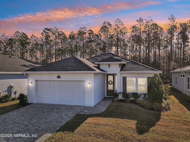 single story home featuring a garage, a front yard, and decorative driveway