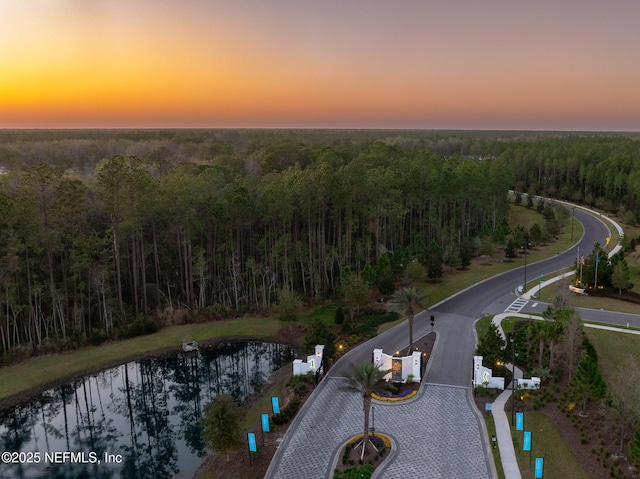 aerial view at dusk with a water view and a forest view