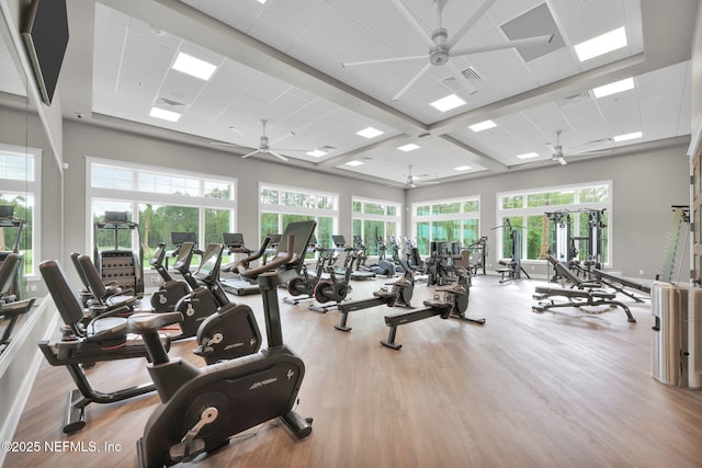 gym featuring a towering ceiling, wood finished floors, ceiling fan, and a paneled ceiling
