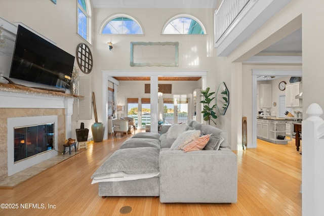 living area with french doors, a towering ceiling, a high end fireplace, wood finished floors, and baseboards