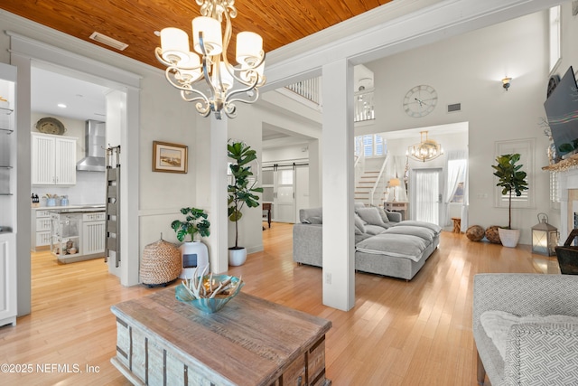 interior space featuring a barn door, wood ceiling, light wood-style floors, stairs, and an inviting chandelier