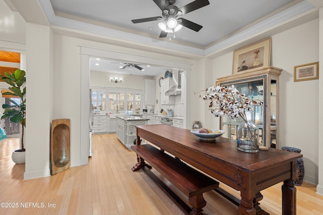 dining area with light wood finished floors, a ceiling fan, baseboards, and crown molding